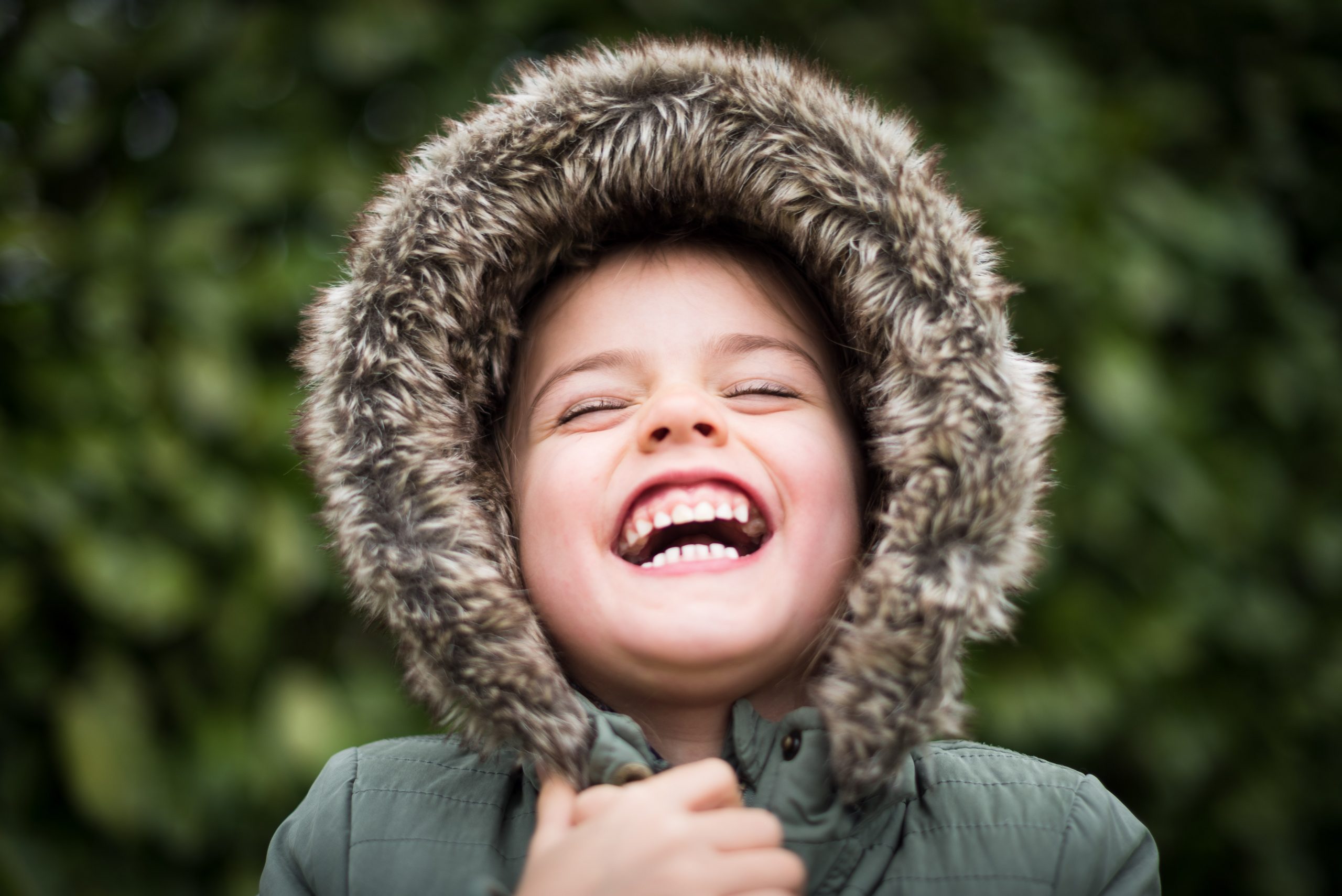 laughing little boy in fur hood