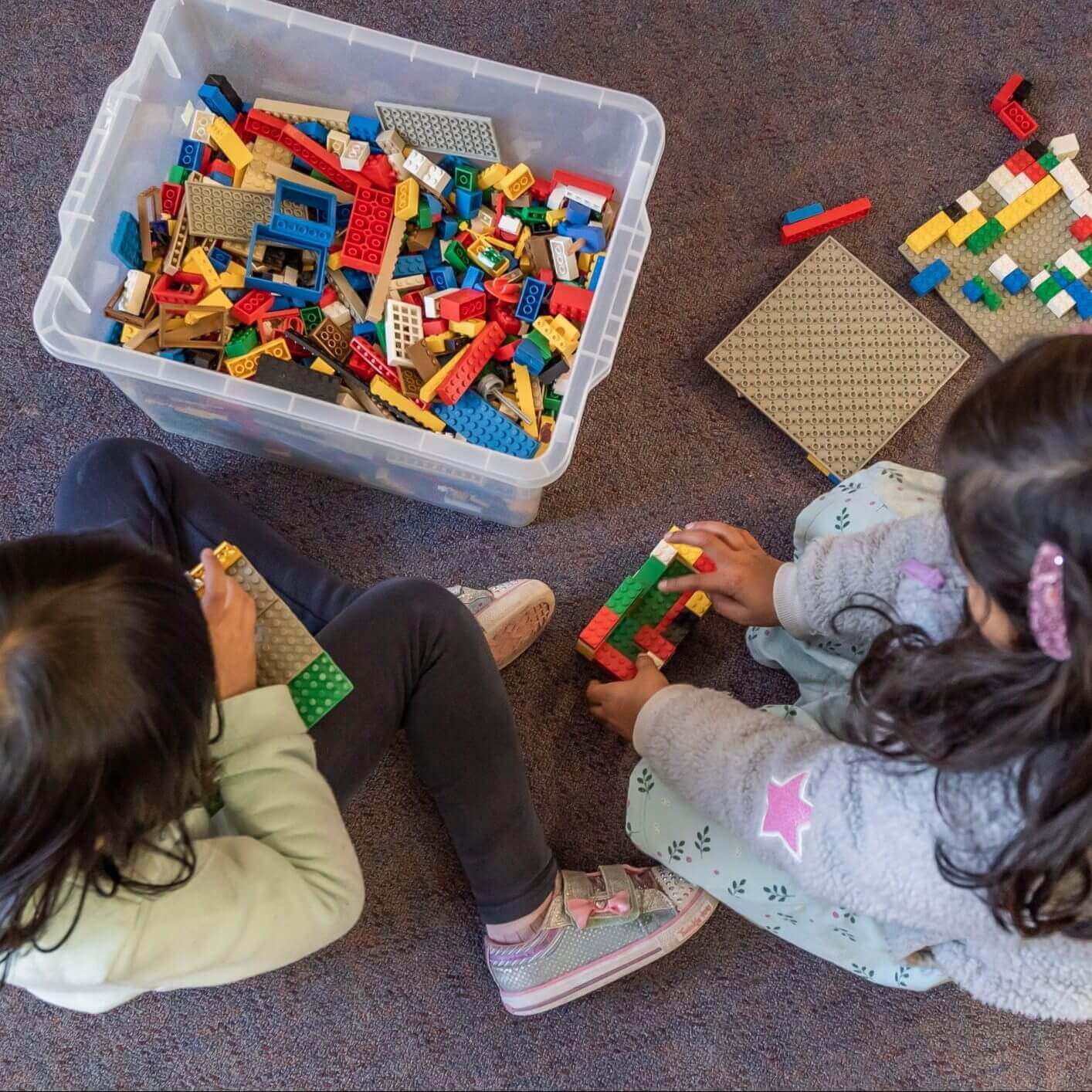 Two little girl playing lego blocks